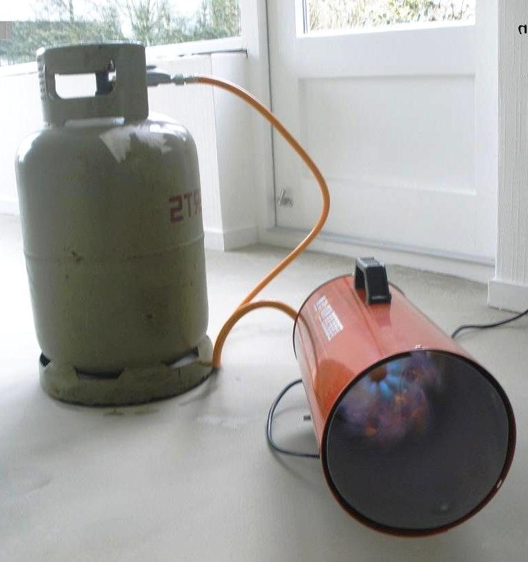 Bouteille de propane debout raccordée à un appareil mobile par un flexible orange pour gaz détendu