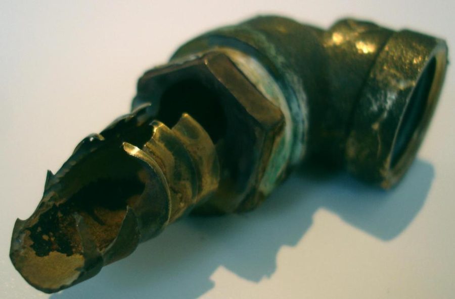 Coude en laiton rongé et perforé par la corrosion acide de l'eau de condensation d'une chaudière gaz