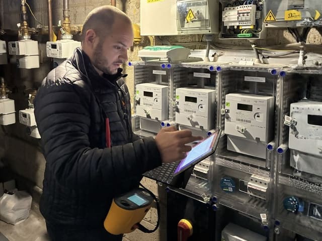 Inspecteur Atlas Contrôle relevant une batterie de compteurs électriques sur tablette lors d'un contrôle en immeuble